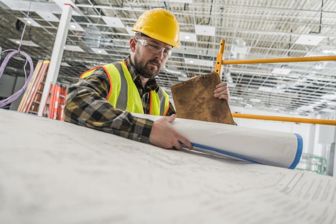 Contractor reviewing building plans and blueprints for a new project
