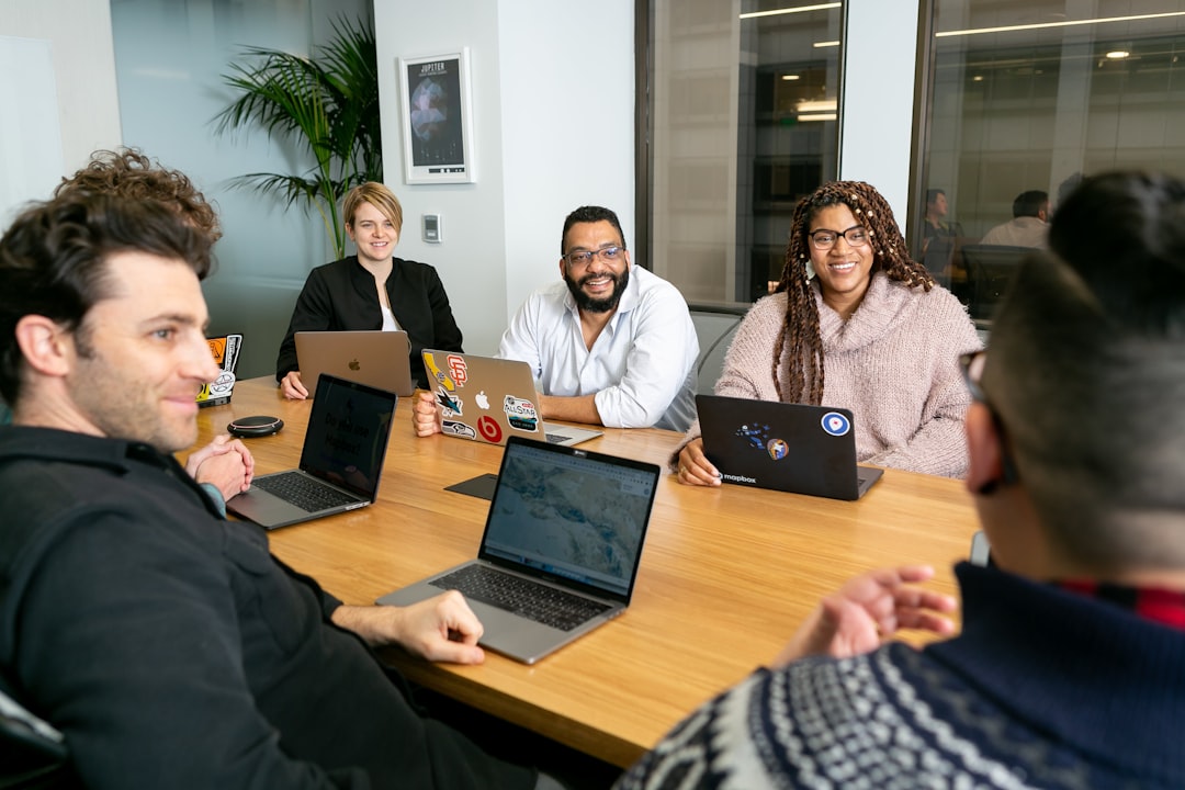 irvine seo company — four people all on laptops, two men and two women, listen to person talking in a board meeting