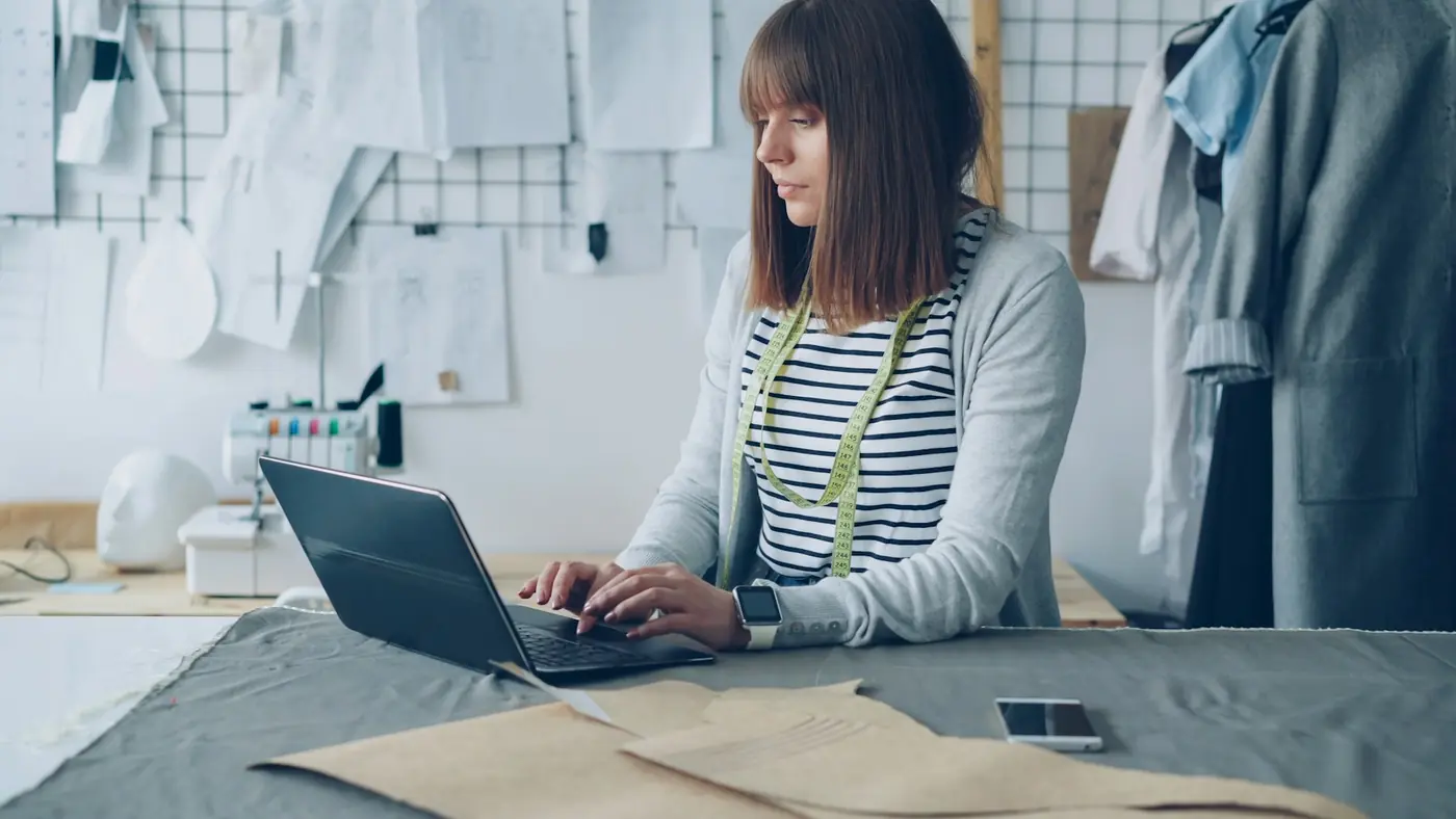 A small-business owner using a laptop in a working studio